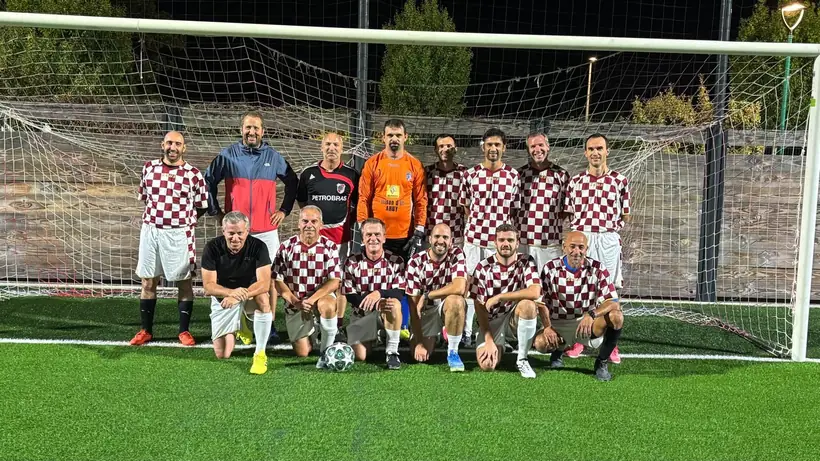 Photo d'équipe en maillot damier rouge et blanc devant le but, de nuit
