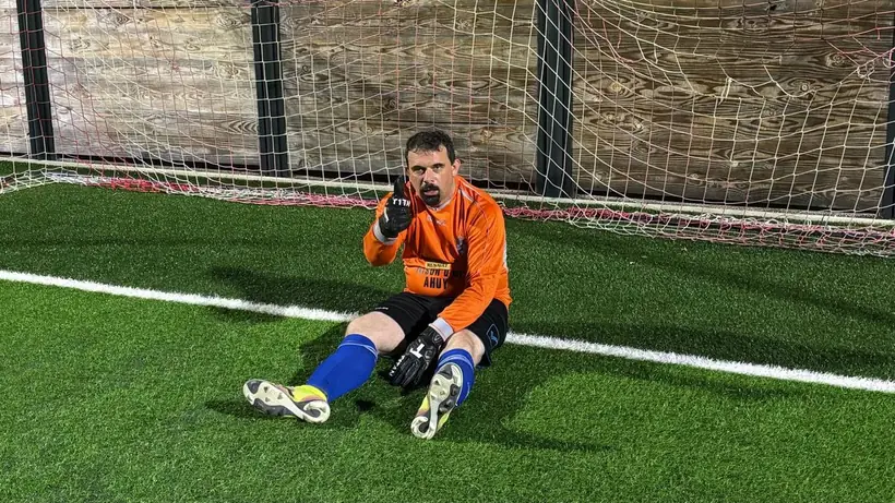 Xav, le gardien, assis dans ses cages en tenue orange