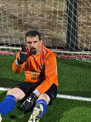 Xav, le gardien, en tenue orange et gants noirs
